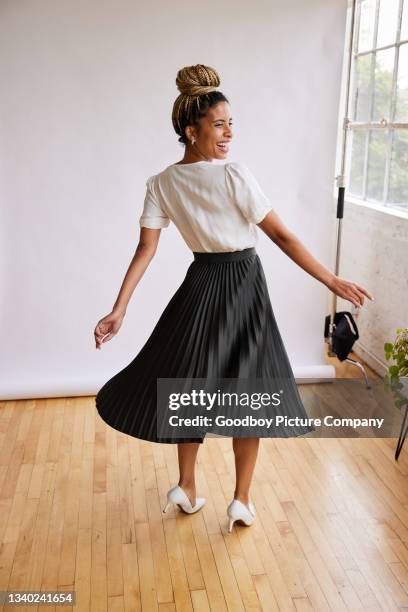 rear view of a smiling woman twirling in a skirt against a white backdrop - black skirt stockfoto's en -beelden