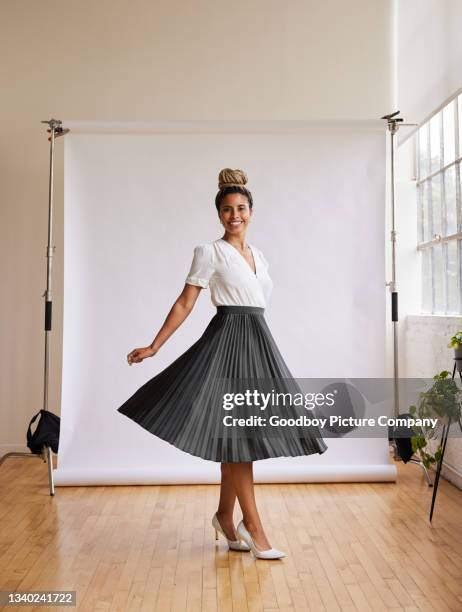 smiling woman twirling in a long skirt against a white backdrop - black skirt stockfoto's en -beelden