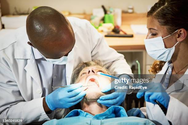 dentist and dental nurse examining a patient reclining with open mouth in the surgery - suction tube 個照片及圖片檔