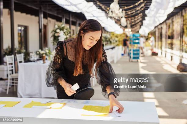 shot of a young woman decorating a table with place card holders in preparation for a wedding reception - wedding planner 個照片及圖片檔