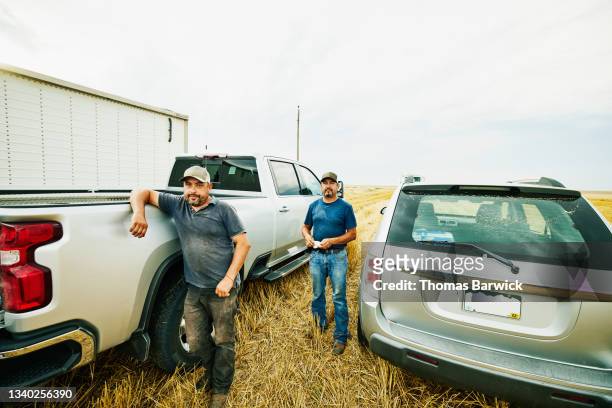 wide shot of farmers standing next to truck in wheat field during summer harvest - autobauer stock-fotos und bilder