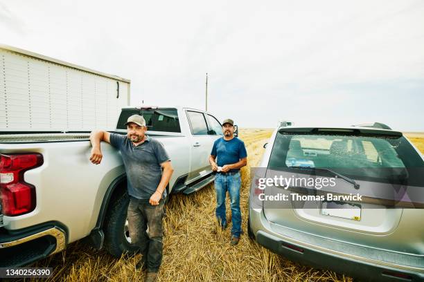 wide shot of farmers standing next to truck in wheat field during summer harvest - naast stockfoto's en -beelden