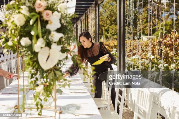 shot of a young woman decorating a table with place card holders in preparation for a wedding reception - event planning stock pictures, royalty-free photos & images