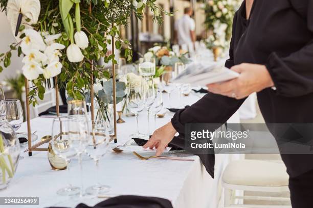 aufnahme einer nicht wiederzuerkennenden frau, die einen tisch in vorbereitung auf eine hochzeitsfeier schmückt - wedding table setting stock-fotos und bilder