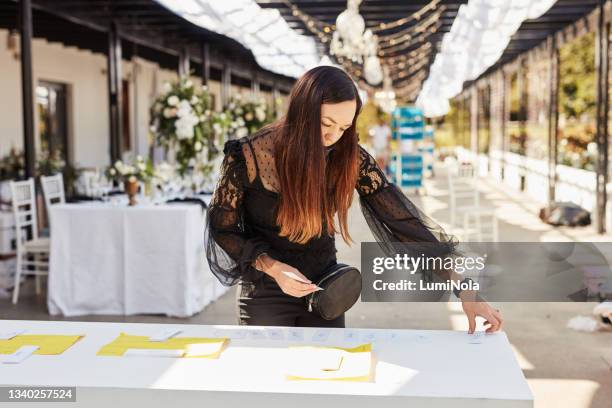 aufnahme einer maskierten jungen frau, die einen tisch mit tischhaltern schmückt, um sich auf eine hochzeitsfeier vorzubereiten - wedding planner stock-fotos und bilder