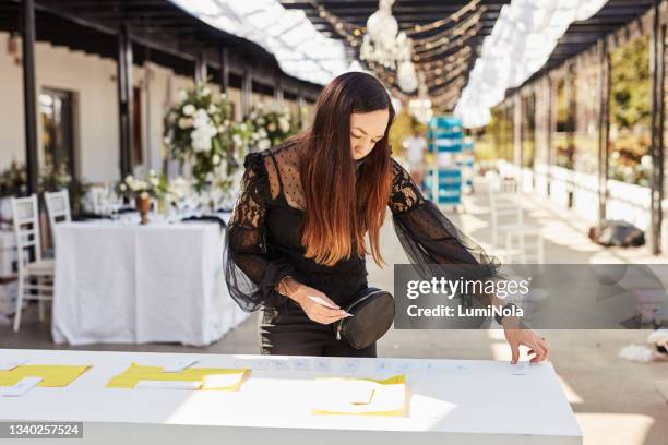 foto de una joven enmascarada decorando una mesa con titulares de tarjetas de lugar en preparación para una recepción de boda - organizador de eventos fotografías e imágenes de stock