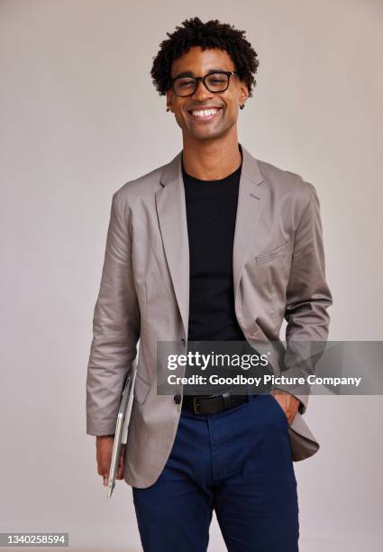 joven empresario con una computadora portátil sonriendo sobre un fondo gris - chaqueta negra fotografías e imágenes de stock