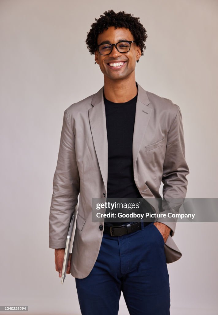 Young businessman with a laptop smiling against a gray background