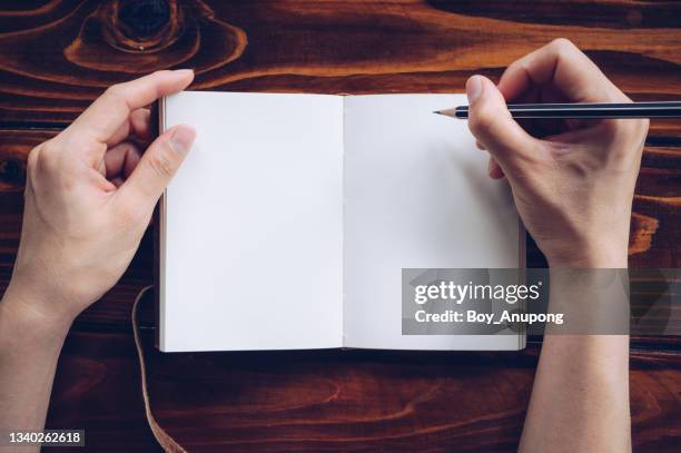 table top view of someone holding a pencil before writing message in blank paper of notebook. - book top view stockfoto's en -beelden