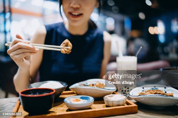 close up, mid-section of young asian woman enjoying delicate taiwanese cuisine with assorted appetitizer plates, soup and iced bubble tea freshly served on dining table in restaurant. asian cuisine and food. eating out lifestyle - taiwanese ethnicity stock-fotos und bilder