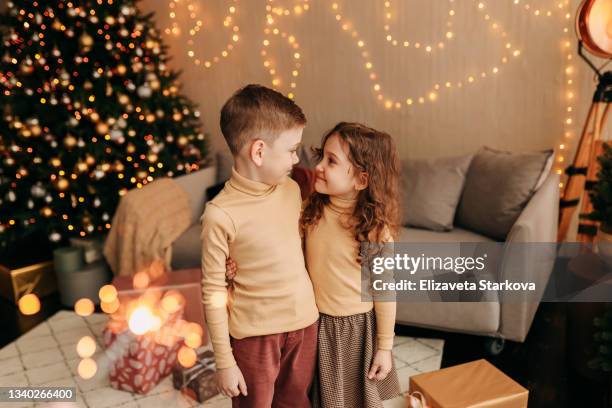 happy funny little children teens friends have fun at home give gift boxes decorate the christmas tree celebrate christmas holidays in a festive interior in a cozy house - funny christmas gift stockfoto's en -beelden