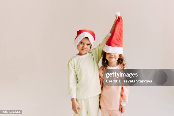 happy funny little children teens friends in santa claus hats decorate a small christmas tree with gifts and balloons celebrate christmas holidays on a white background - happy holidays family stock pictures, royalty-free photos & images