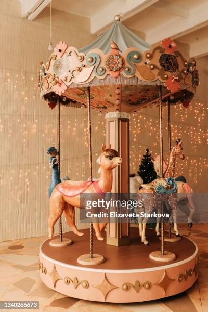 funny kids teen friends a little girl and a little boy ride together on a merry-go-round with horses on the background of garlands and a christmas tree in an amusement park in the new year - carousel horse stock pictures, royalty-free photos & images