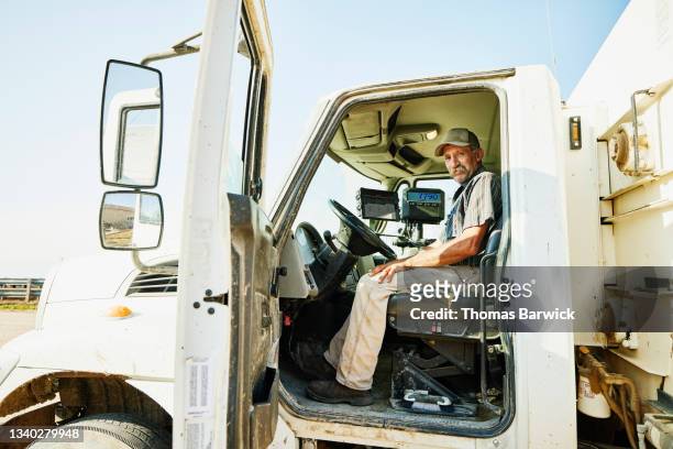 Wide shot portrait of farmer preparing to feed cattle from feed truck on farm