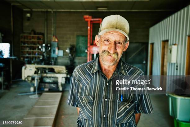 Medium shot portrait of smiling farmer in repair shop on farm