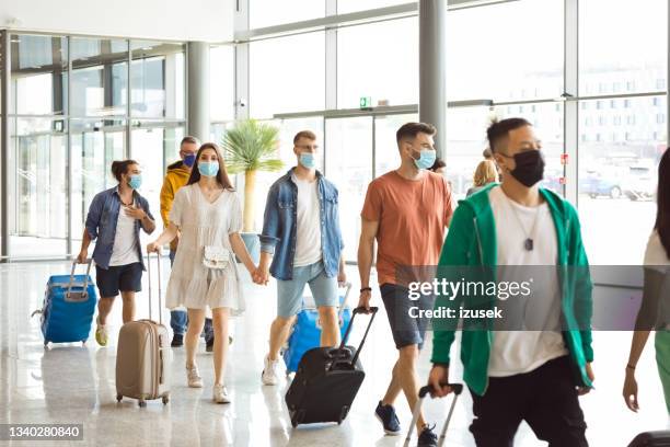 passengers at the airport with luggage, wearing n95 face masks - crowded airport stock pictures, royalty-free photos & images