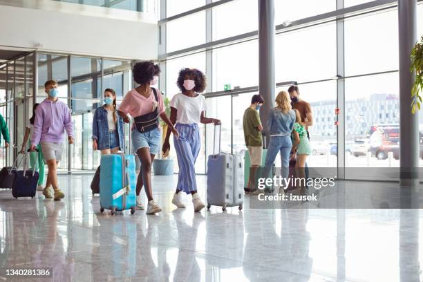 passagiere am flughafen mit gepäck, tragen n95 gesichtsmasken - african mask stock-fotos und bilder