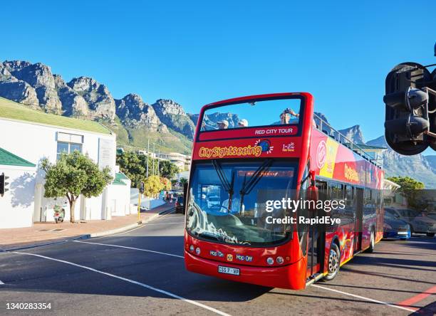 bright red tourist bus driving into camps bay, cape town, south africa - open top bus stock pictures, royalty-free photos & images