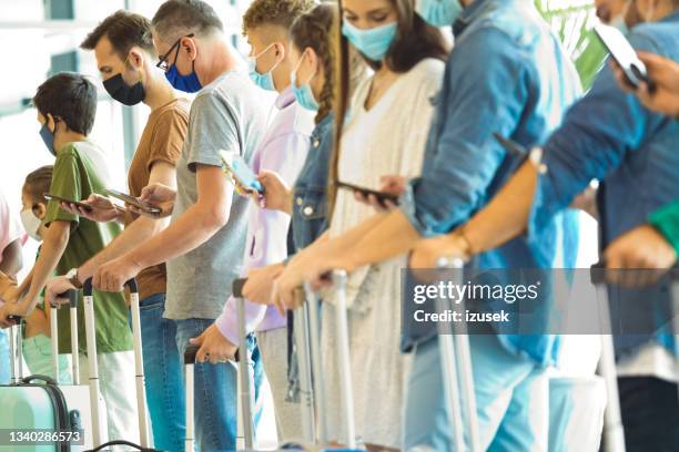 travelers waiting in line at airport terminal - airport covid stock pictures, royalty-free photos & images