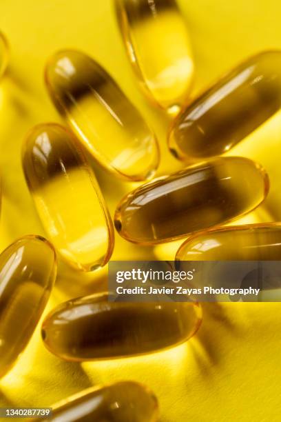 some omega-3 fatty acids pills on yellow background - fish oil stock photos et images de collection