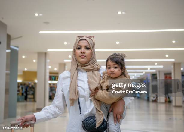 muslimische mutter, die mit ihrer tochter durch den flughafen wacht - fat hips stock-fotos und bilder