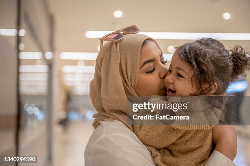 Muslim mother kissing her young daughter