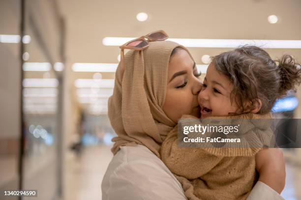 muslim mother kissing her young daughter - woman flying scarf stock pictures, royalty-free photos & images