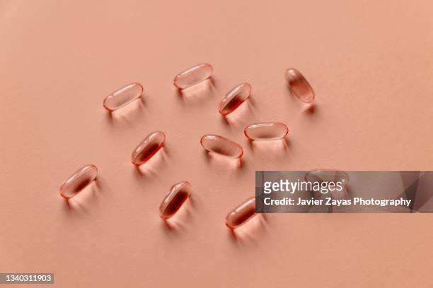 some omega-3 fatty acids pills on red background - fish oil stock photos et images de collection