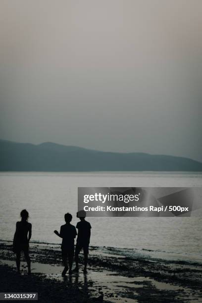 silhouette of people standing at beach against sky,megalochori,greece - megalochori stock-fotos und bilder