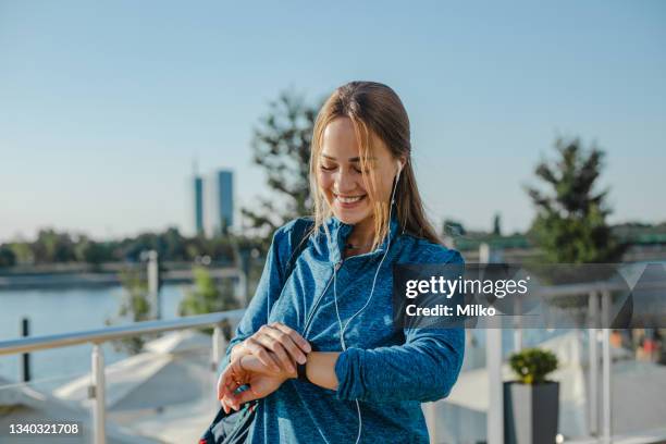 young woman in a sports wardrobe using sports watch - pedometer stock pictures, royalty-free photos & images