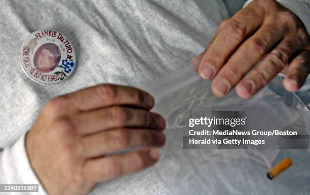 Dorchester, MA. Joe Del Tufo holds a cigarrette bud he recovered from the suspected murderer of his brother Frankie as he wears a pin in his memory...