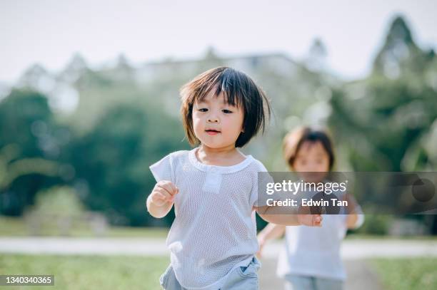 twin asian chinese baby boys running toward camera in public park during summer weekend morning happily - asian twins 個照片及圖片檔