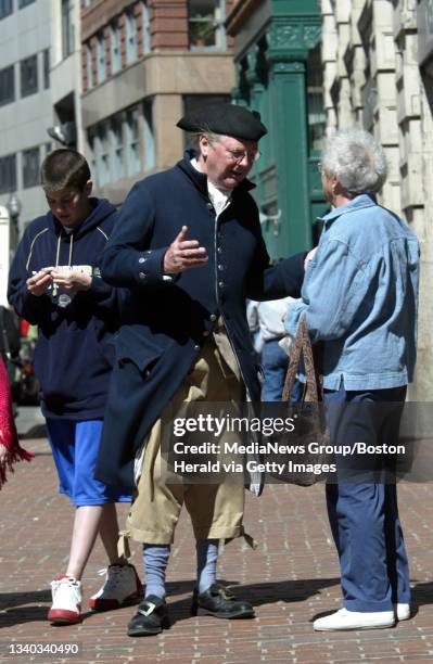 Donald Watson, a tour guide with the Freedom Trail Foundation, helps a tourist on Washington St. In downtown Boston on the birthday of the city.
