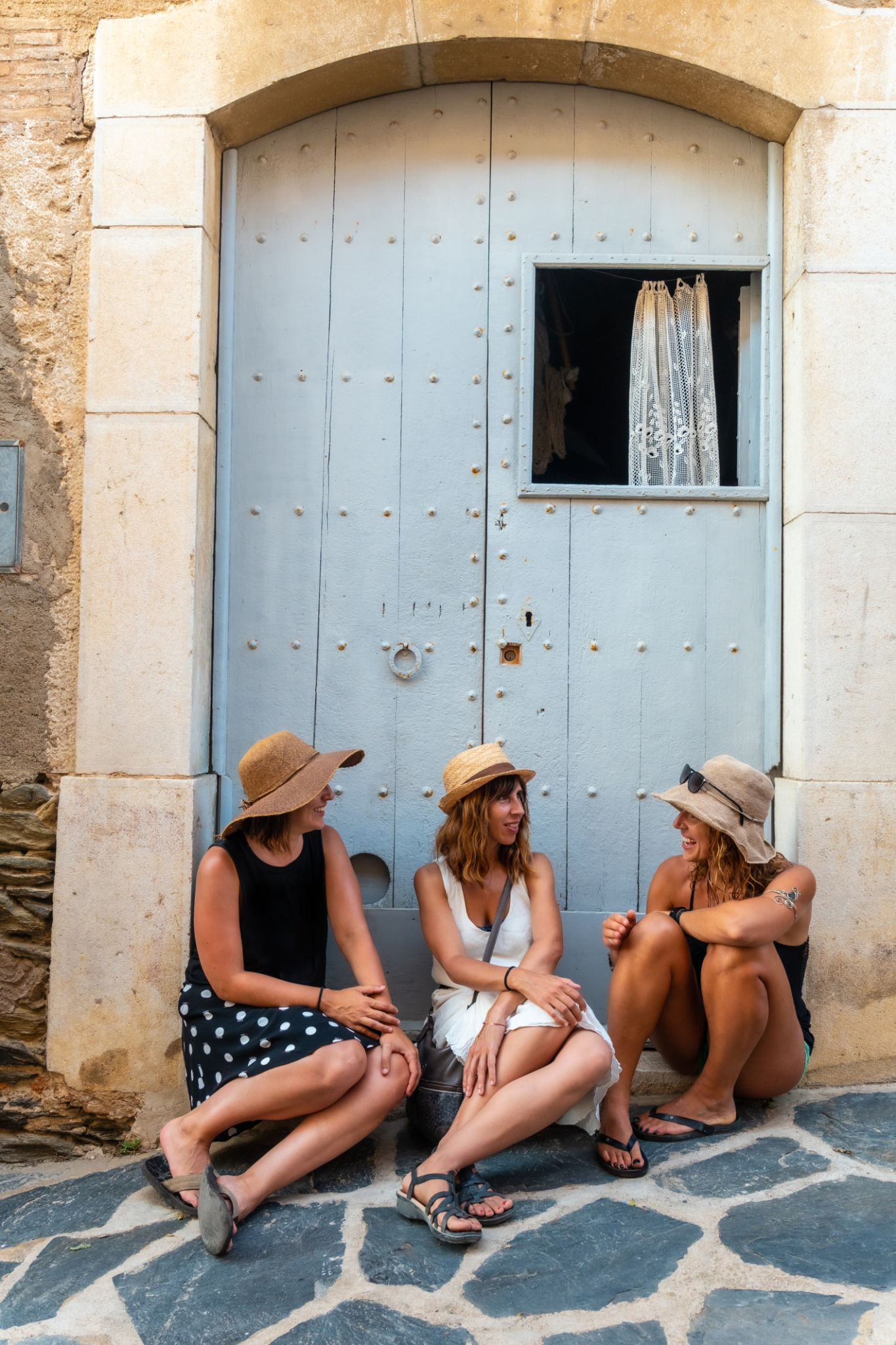 Girlfriends in summer enjoying the holidays. Two sisters with a sister sitting on a wooden door enjoying the Mediterranean Girlfriends in summer enjoying the holidays. Two sisters with a sister sitting on a wooden door enjoying the Mediterranean