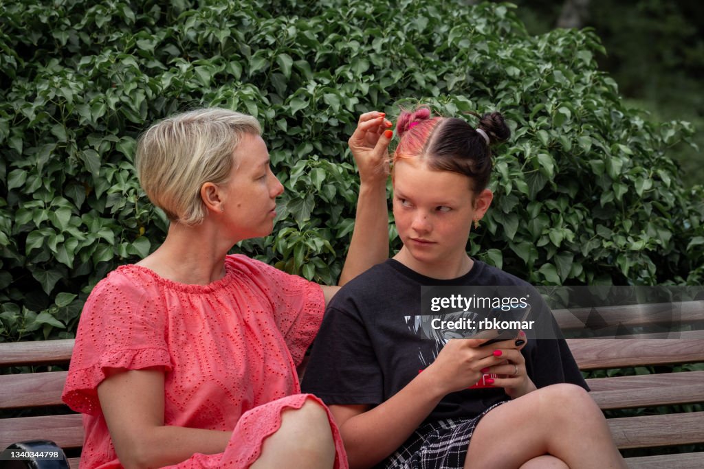 Conflict of caring single mother and a irritation teenage daughter in the park