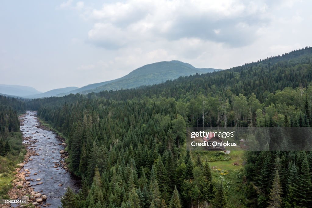 Vue aérienne de la forêt boréale, de la rivière et de la cabane en rondins en été, Québec, Canada