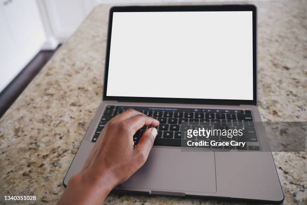 woman works on laptop at kitchen island - ígnea fotografías e imágenes de stock
