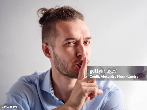 white young man makes secret, silence, shh sign confidently - man finger on lips stock pictures, royalty-free photos & images