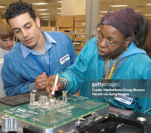 North Reading, MA-- Test engineer Peter Romano, left, guides Snowden High School's Chantaylor Perkins-King as she tests a chip at Teradyne Wednesday...