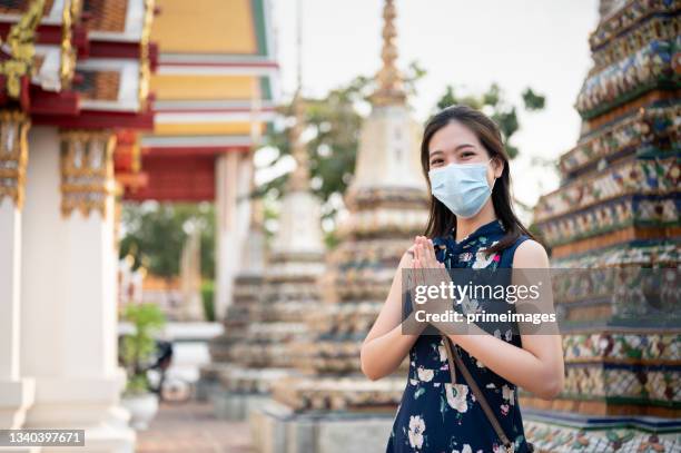 new normal lifestyle travel concept praying '' sawasdee ''around temple wide angle shot asian tourist with facemask face mask protective dust pm 2.5 at chinese temple wat arun in bangkok thailand - wat imagens e fotografias de stock