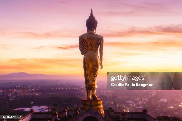 the iconic standing buddha statue in wat phra that khao noi with sunrise and the mist, nan province, thailand - wat imagens e fotografias de stock