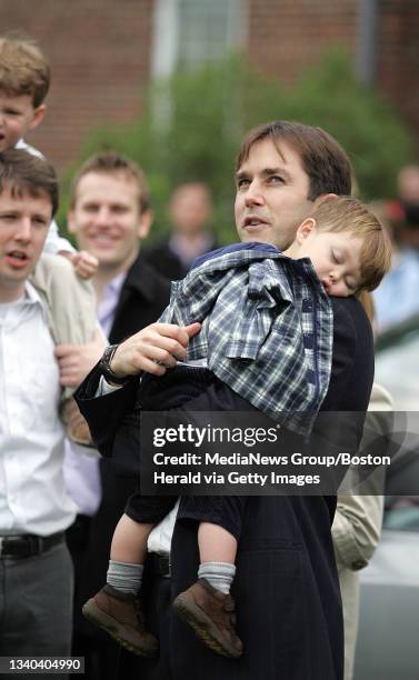 The bishop of the church, Patrick O'Loughlin, holds his son Ryan, as they watch their church, the Jesus Christ Church of Latter-Day Saints on...