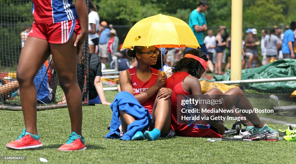 (051715 Newton, MA) Iodine Felix and Lourdes Jean-Louis (cq) of Somerville hide from the hot sun under an umbrella  as they wait for their race during the Division 1 state track relays at Newton SouthHigh School in Newton. (Sunday,May 17, 2015). Staf