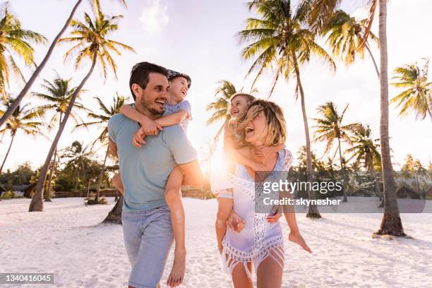 familia despreocupada divirtiéndose mientras se mete en la playa. - familia en la playa fotografías e imágenes de stock