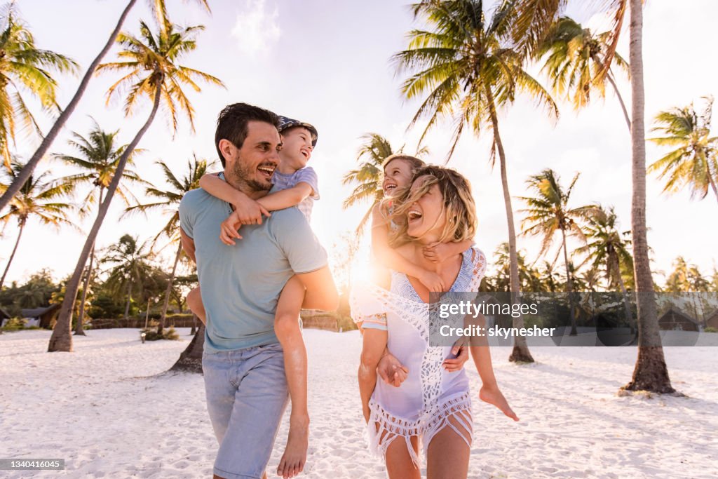 Carefree family having fun while piggybacking on the beach.