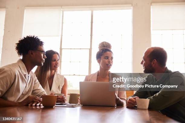diverse businesspeople talking during a meeting at an office table - corporate modern office bright diverse imagens e fotografias de stock