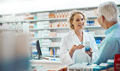 Cropped shot of an attractive young chemist helping a senior male customer in her pharmacy