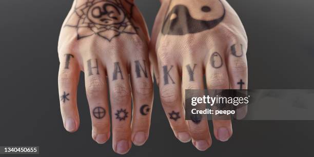 two tattooed hands with relaxed fingers spelling "thank you" and religious symbols - religieus icoon stockfoto's en -beelden