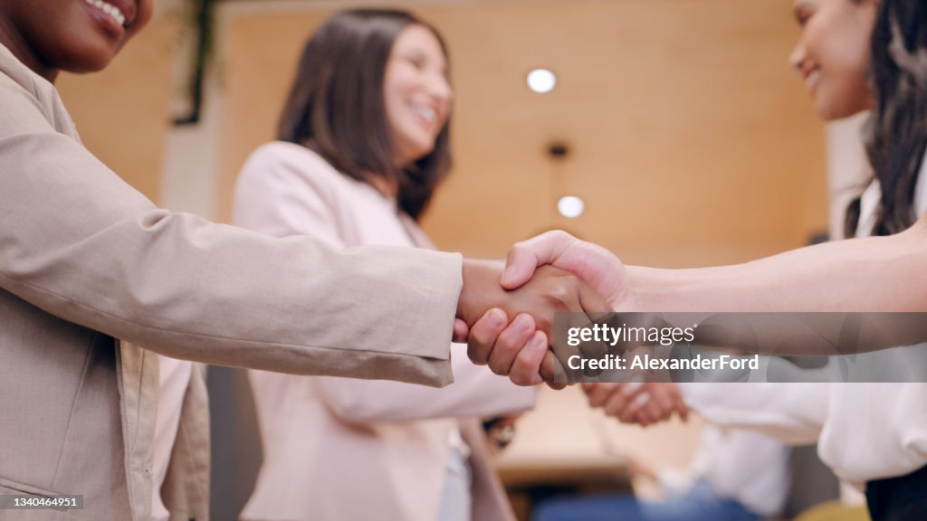 Shot of an unrecognizable group of businesspeople standing in the office together and shaking hands during a discussion