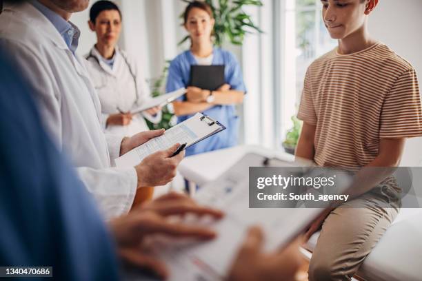 meeting of doctor where they are examining the patient and taking notes of his medical condition in medical chart - doctor with male patient reading notes stock pictures, royalty-free photos & images